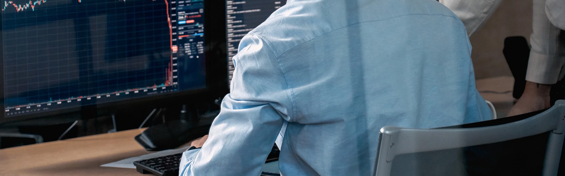man sitting by desk in front of computer